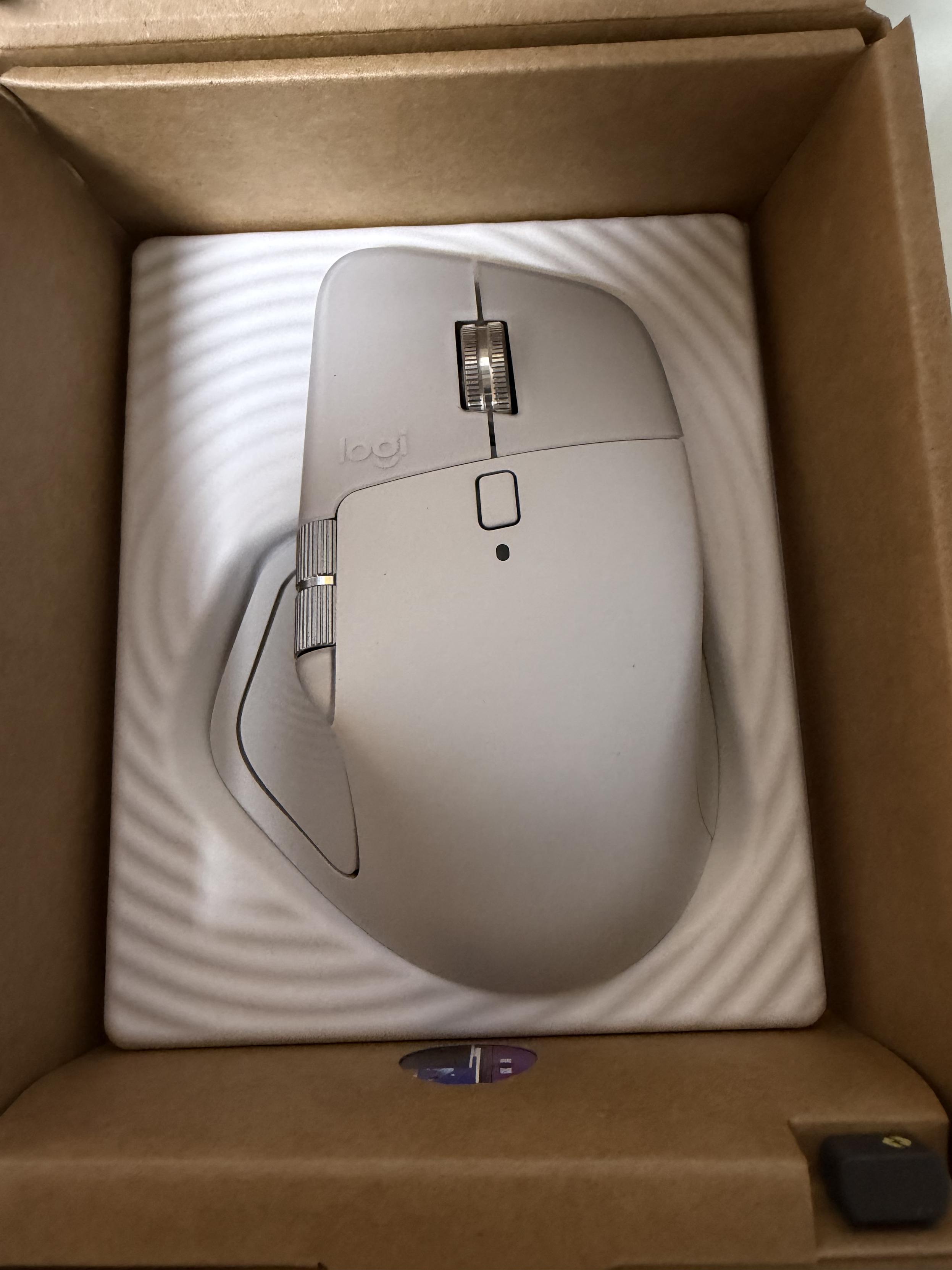 흰색 로지텍 마우스와 USB 리시버가 종이 상자에 포장되어 있습니다.